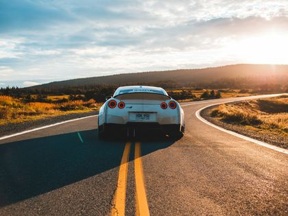 Sportcoupé von hinten auf einer Landstraße im Abendlicht