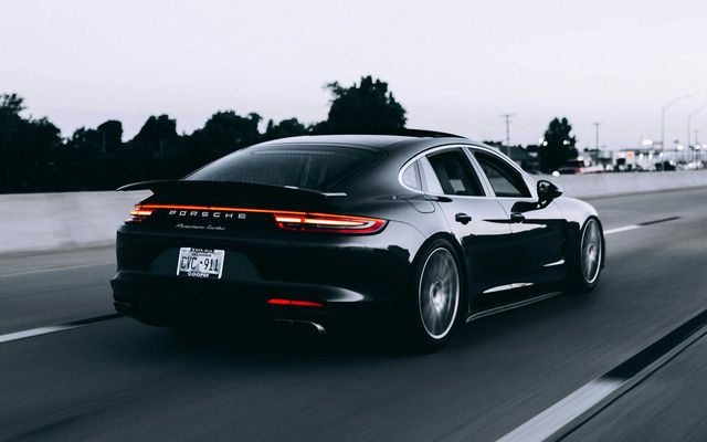 Dunkle Sportlimousine mit hochglänzender Folierung auf der Straße